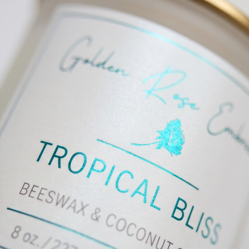 Tropical Bliss 8oz Beeswax Candle. 
Frosted glass jar, Gold metallic lid. Woodwick. 
Notes of Mango, Orange, Pineapple, Blood Orange, Peach, Banana, Apple, Coconut, Tonka, Vanilla, Green, Rose, Jasmine, Violet, Lavender, Resin, Musk, Paprika, Red Pepper, Pimento Leaf, Black Tea, Teakwood, Vetiver, and Golden Amber. A heavenly tropical aroma of guava, passionfruit, mango, pineapple, and coconut. Custom beeswax candle blended with organic coconut oil and nontoxic fragrances and essential oils.