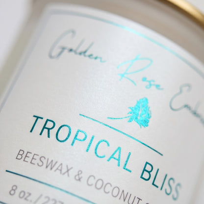 Tropical Bliss 8oz Beeswax Candle. 
Frosted glass jar, Gold metallic lid. Woodwick. 
Notes of Mango, Orange, Pineapple, Blood Orange, Peach, Banana, Apple, Coconut, Tonka, Vanilla, Green, Rose, Jasmine, Violet, Lavender, Resin, Musk, Paprika, Red Pepper, Pimento Leaf, Black Tea, Teakwood, Vetiver, and Golden Amber. A heavenly tropical aroma of guava, passionfruit, mango, pineapple, and coconut. Custom beeswax candle blended with organic coconut oil and nontoxic fragrances and essential oils.